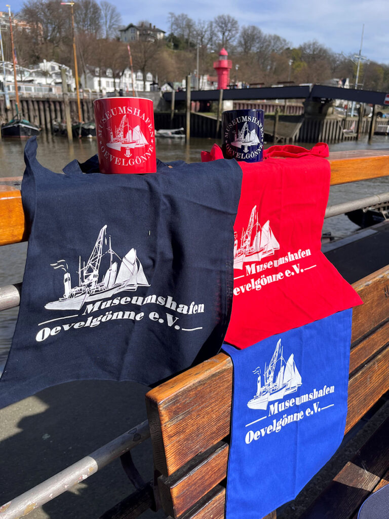 Mehrere Artikel aus dem Shop auf einer Sitzbank im Hafen