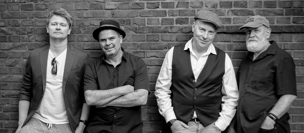 Foto der Bandmitglieder vor einer Hauswand stehend